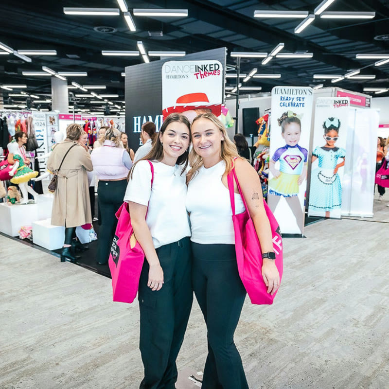 Two teachers with DTE tote bags at an exhibitor booth